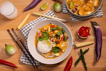 red curry with jasmine rice on a pine table with ingredients spread on the table 
