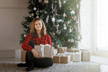Teenage girl with gifts under the tree