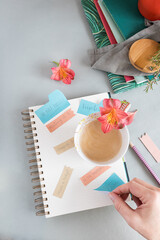 Empty spiral notebook full of multicolor reminder notes and a foamy coffee with a flower over it on...