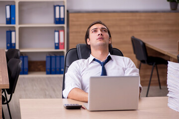 Obraz premium Young male employee unhappy with excessive work in the office