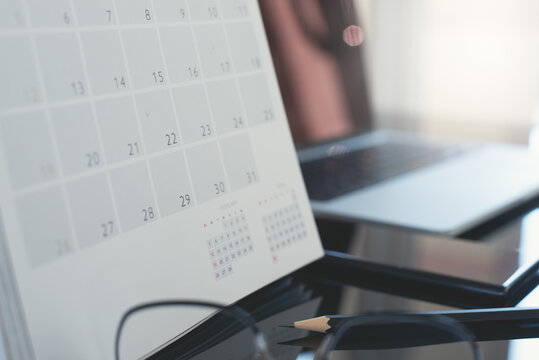 Closeup of calendar and laptop computer and mobile phone on table in office with nobody - Powered by Adobe