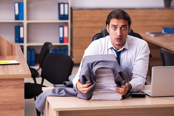 Obraz premium Young male employee unhappy with excessive work in the office