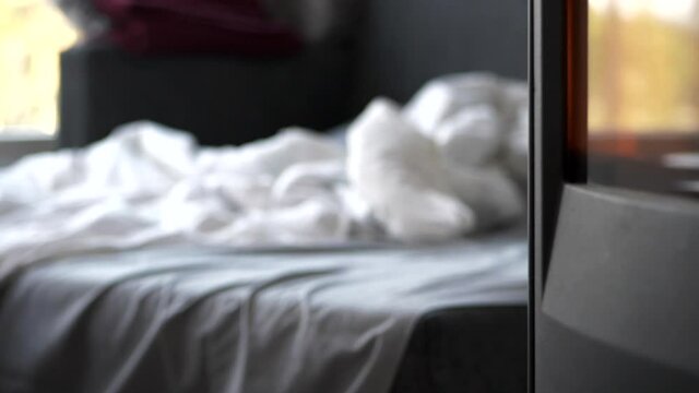 Unmade bed next to fireplace. Focus on foreground