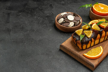 Half shot of tasty cakes cut lemons with biscuits on cutting board on dark table