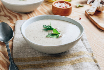 Mushroom cream soup in gray bowls with parsley on wooden background