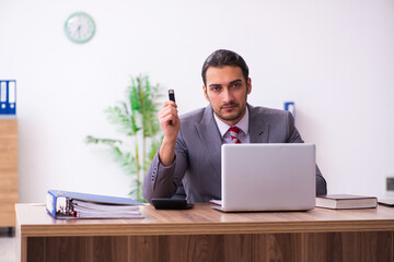 Young male employee inserting flash drive into laptop