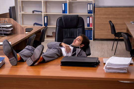 Young male employee sleeping at workplace