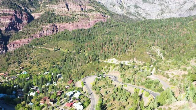 Aerial Drone Rising Motion of Beautiful Ouray Colorado Pine Tree Forest and Mountain Cliffs with Cars Driving on Highway 550 by Rocky Mountain Houses
