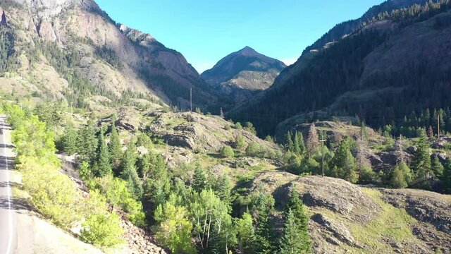 Aerial Drone Rising Motion of Cars Driving on Highway 550 Through Ouray Colorado Mountains to Hiking Trails Surrounded by Thick Pine Tree Forest and Power Lines