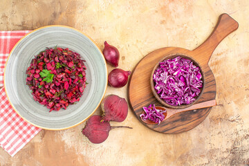 Fototapeta na wymiar top view vegetable salad with green leaves with beetroots red onions and bowl of chopped cabbage on a wooden background with space for text