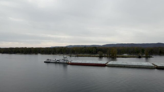 Barge on the Mississippi River. Industrial boat with cargo standing still on the river canal. Slow rear pan of a barge
