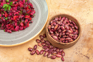Horizontal view of delicious salad with beetroot and bean and beans inside and outside of pot on mixed color background