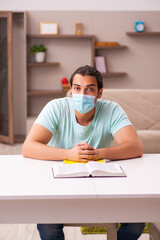 Young male student studying at home during pandemic