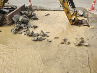 Excavators dig holes to destroy concrete roads to repair damaged water pipes. 