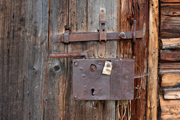 Old ferruginous lock on the wooden doors of barn