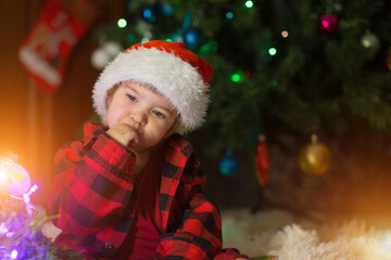 a child in red clothes is sitting waiting for the new year. the concept of celebrating Christmas at midnight. holiday costume