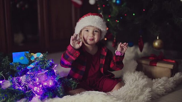 a child in red clothes is sitting waiting for the new year. the concept of celebrating Christmas at midnight. holiday costume