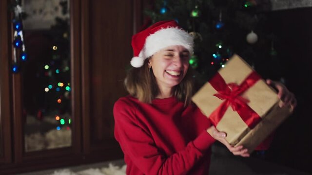 girl in red clothes unfold New year gifts. the concept of celebrating Christmas midnight. Holiday's decor boce, Christmas tree