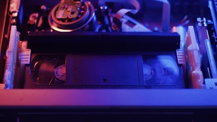 A wide shot of a VHS tape inserted into a VCR. The tape is played and fast forwarded at different speeds.