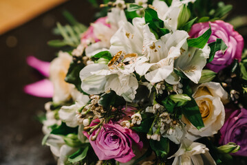 two gold wedding rings with diamonds lie on bouquet
