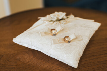 two wedding gold rings of the bride and groom for engagement lie on the decorated cushion
