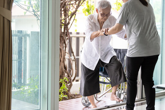Asian caregiver help care to senior grandmother walk,woman holding hands of the old elderly for support,walking up from a different level floor,safety,prevent accident at nursing home,service concept.