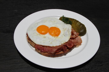 Fototapeta na wymiar Famous German meal called Strammer Max. Fried eggs and ham on sourdough bread, served with gherkins