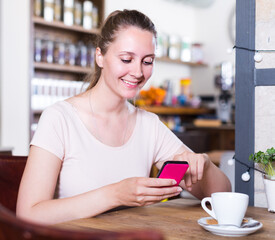 Girl is sitting in cafe and watching in phone.