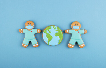 two gingerbread man medics in a mask with the gingerbread planet earth on a blue background