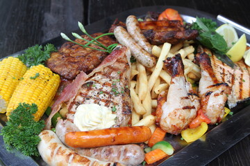 Summer grill platter with different meats, sausages and vegetables. Served with vegetables and French fries.
