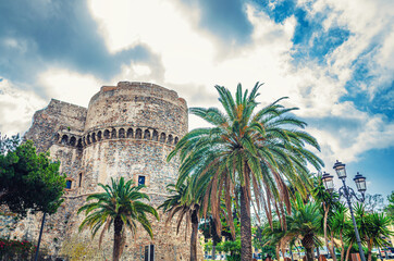 Aragonese Castle Castello Aragonese stone medieval buildings and palm trees in Piazza castello...