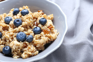 Bowl with tasty sweet oatmeal, closeup