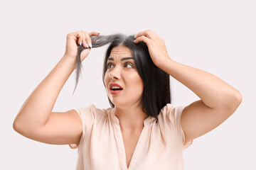Stressed woman with graying hair on light background