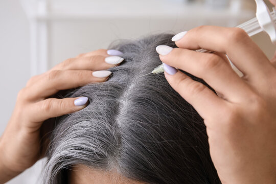 Woman with graying hair using serum at home, closeup