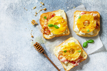 Healthy breakfast or snacks. Toast with caramelized pineapple, bacon, nuts, and ricotta on a slate background. Top view flat lay. Copy space.