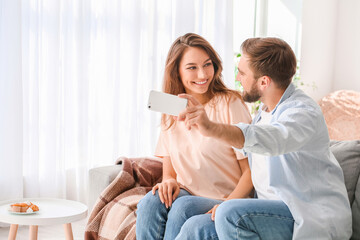 Fototapeta premium Young couple taking selfie at home