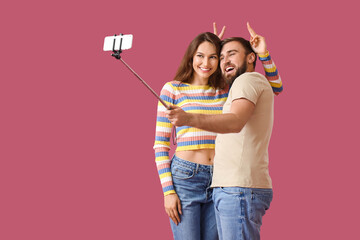 Young couple taking selfie on color background