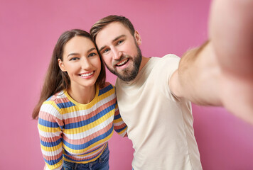 Fototapeta premium Young couple taking selfie on color background