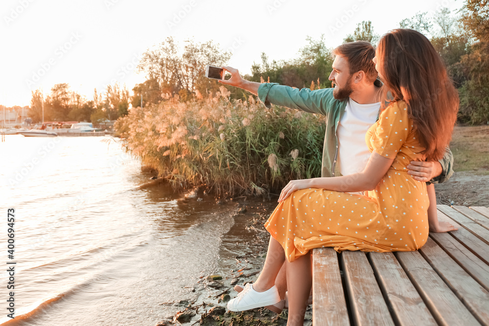 Wall mural Young couple taking selfie near river