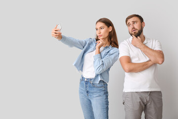 Young couple taking selfie on light background