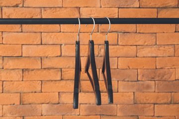 Rack with clothes hangers near brick wall