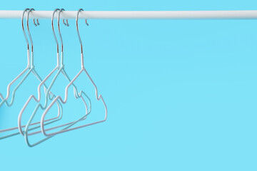 Rack with clothes hangers on color background