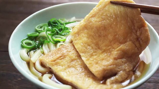 きつねうどんの油揚げを箸で持ち上げる