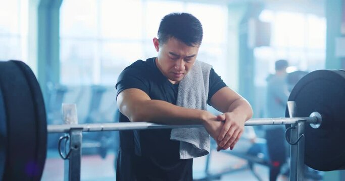 Exhausted chiese sportsman leaning on barbell press bench breathing heavily after intense weightlifting exercise workout training at gym concept.