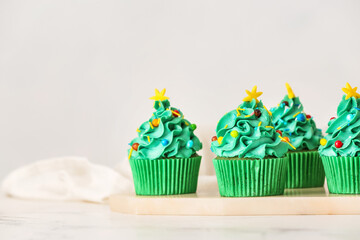 Tasty Christmas cupcakes on table