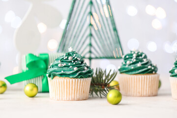Tasty Christmas cupcakes on table
