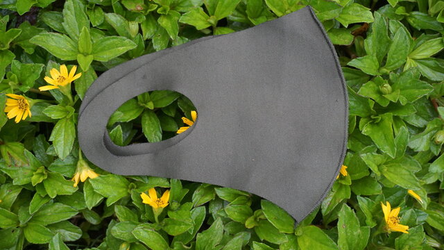 fask mask green color with background at grass and beautiful yellow flowers
