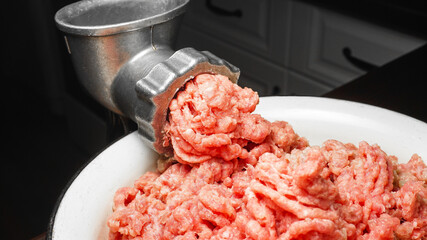 Meat grinder in action and ground beef meat. Horizontal close-up color image of process of grinding preparation of minced raw red meat in Grinder. photo