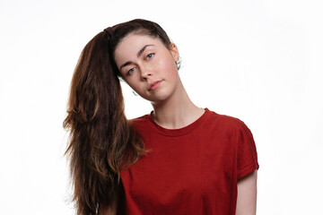 Portrait of a young caucasian woman with a ponytail hanging over her head. White background. The concept of unruly hair and its care