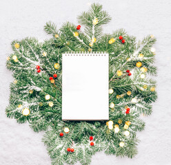 Fototapeta na wymiar Blank notebook for planning goals on New Year's green branches with lights